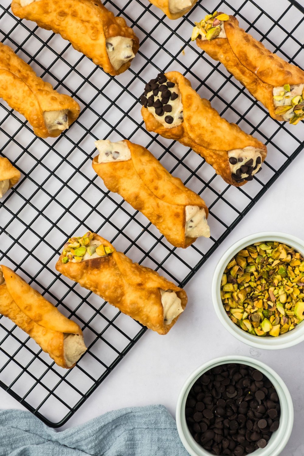 Vegan cannoli with crushed pistachios and mini chocolate chips being added as garnish.