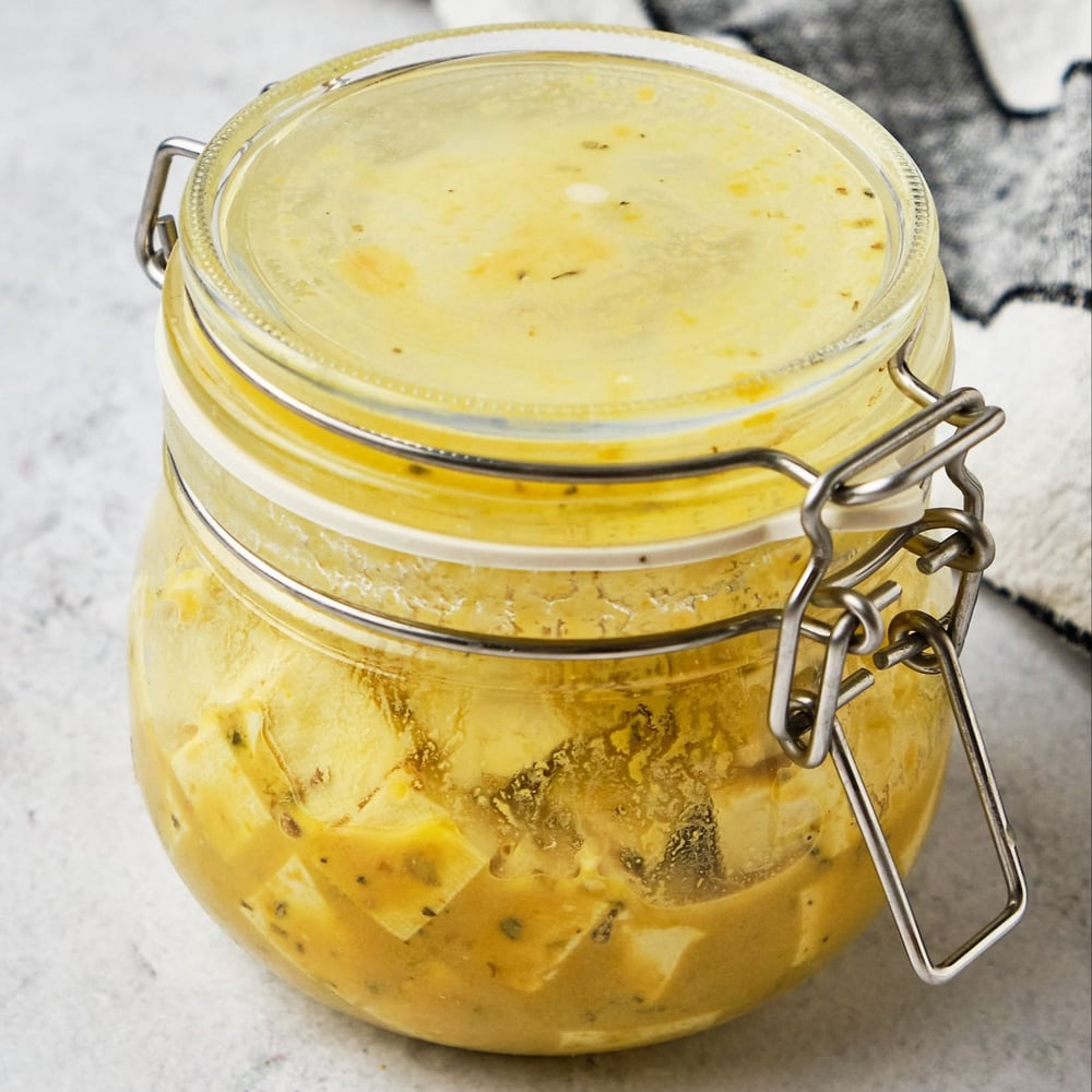 Tofu pieces in a jar with the feta marinade.