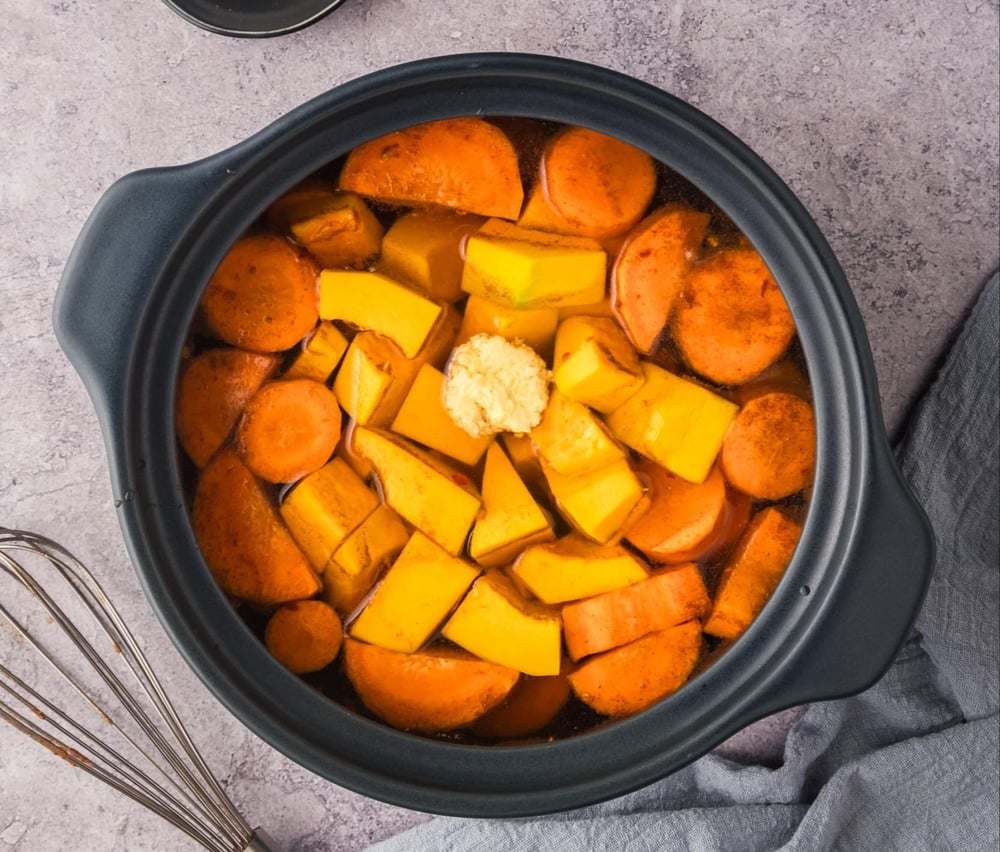 Carrots, pumpkin, and ginger added into the pot with broth.
