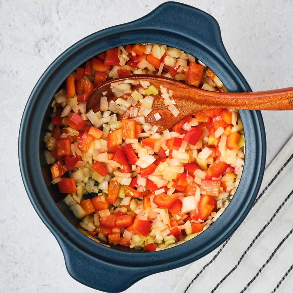 Chopped onions, bell peppers, and garlic, cooked in a pot.